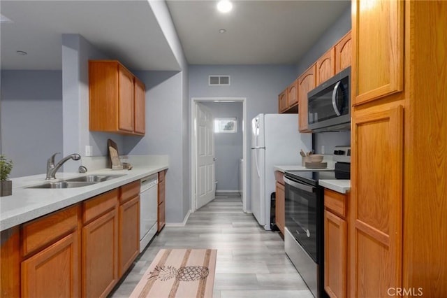 kitchen featuring stainless steel appliances, light hardwood / wood-style floors, and sink