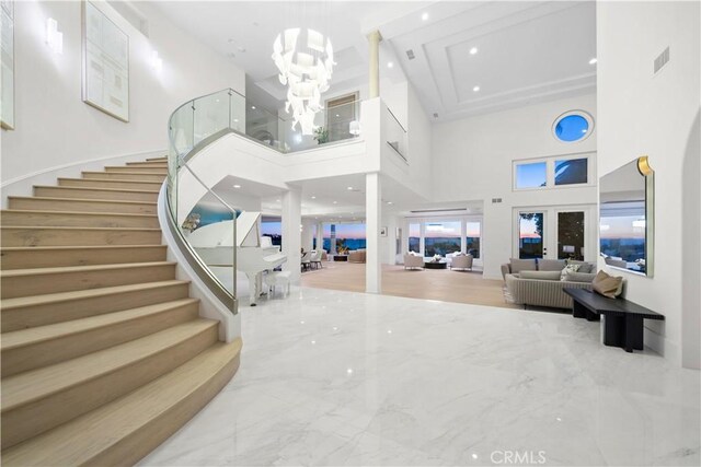 entryway featuring a towering ceiling, french doors, and a notable chandelier