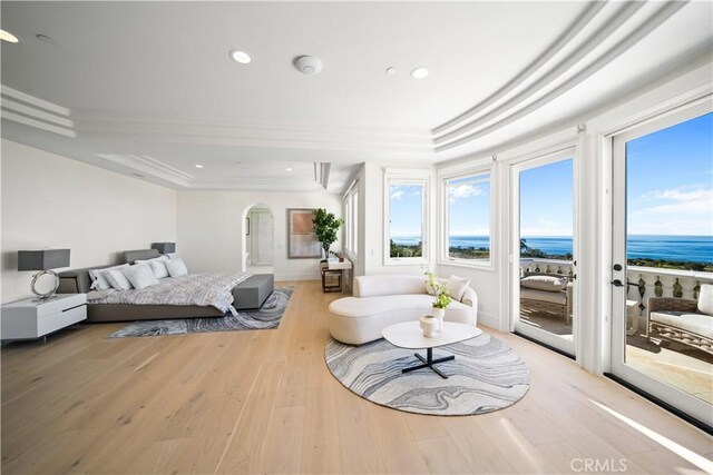 bedroom featuring light hardwood / wood-style floors, ornamental molding, access to outside, and a water view