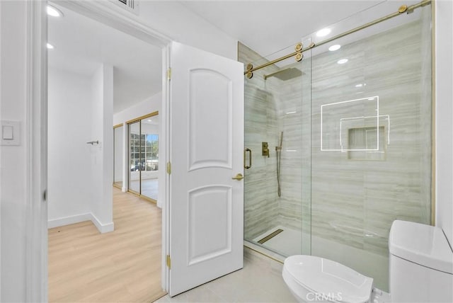 bathroom with toilet, a shower with door, and hardwood / wood-style flooring