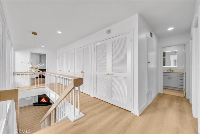 hall with light wood-type flooring and sink