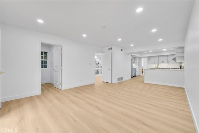 unfurnished living room with sink and light hardwood / wood-style flooring