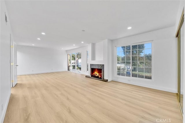 unfurnished living room featuring a premium fireplace and light wood-type flooring