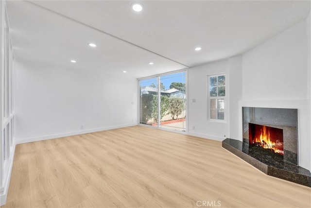 unfurnished living room with a tiled fireplace and light hardwood / wood-style flooring