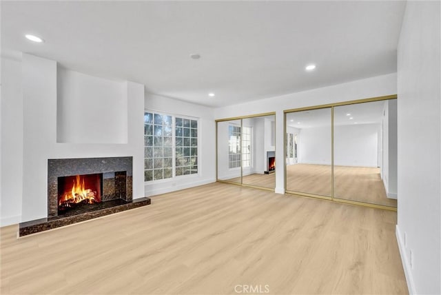 unfurnished living room featuring light hardwood / wood-style floors and a high end fireplace