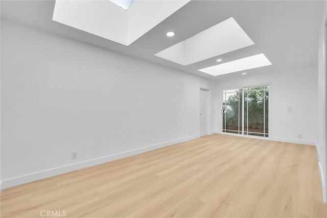 spare room featuring light hardwood / wood-style floors and a skylight