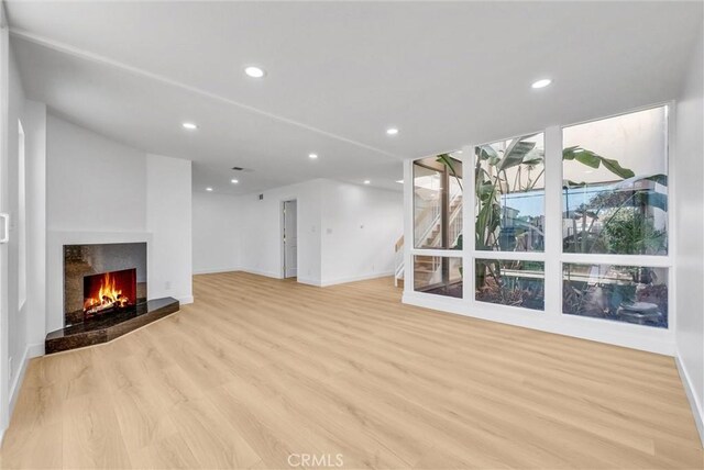 unfurnished living room with a fireplace and light hardwood / wood-style floors