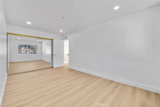 unfurnished bedroom with light hardwood / wood-style flooring and a closet