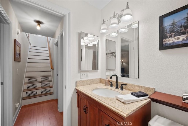 bathroom with wood-type flooring, vanity, and an inviting chandelier