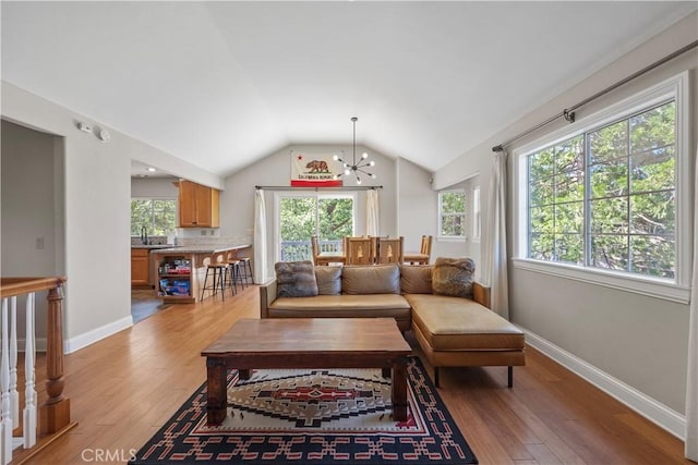 living room featuring light hardwood / wood-style floors, sink, a notable chandelier, and vaulted ceiling