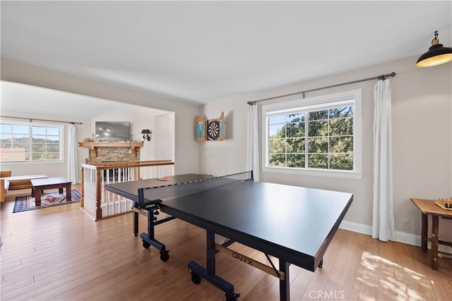 game room featuring light wood-type flooring and a fireplace