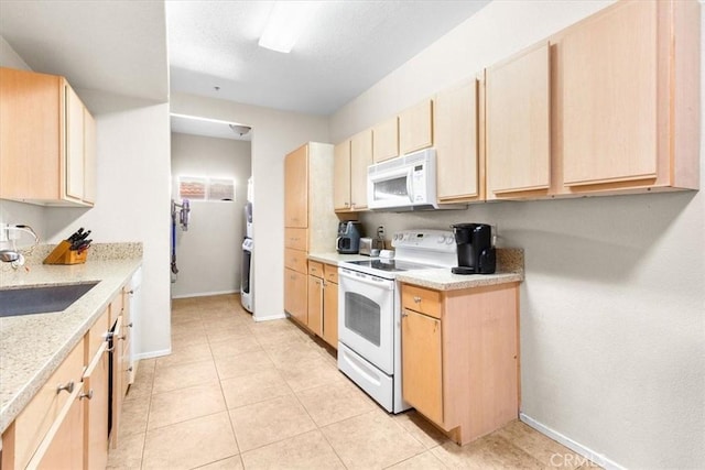 kitchen with light brown cabinets, light stone counters, sink, and white appliances