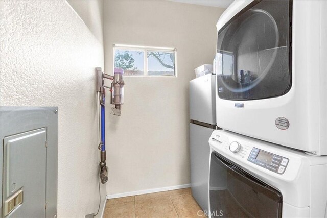 laundry area featuring stacked washing maching and dryer and light tile patterned floors