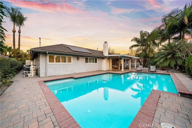 pool at dusk with a patio area