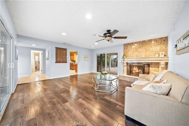 living room with ceiling fan, a textured ceiling, wood-type flooring, and a high end fireplace