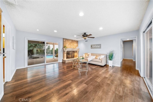 living room with ceiling fan, a fireplace, a textured ceiling, and dark hardwood / wood-style floors