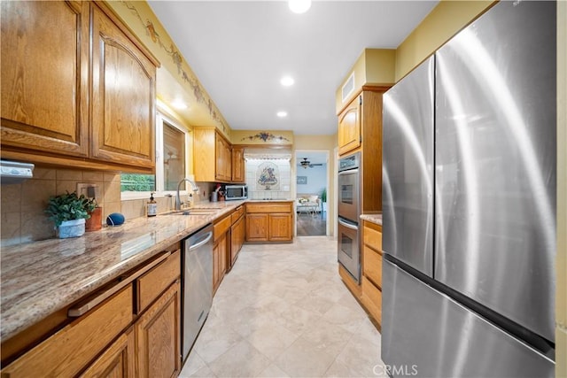 kitchen featuring backsplash, light stone countertops, sink, and stainless steel appliances