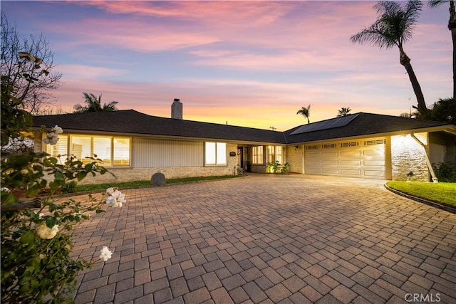 ranch-style home with a garage and solar panels