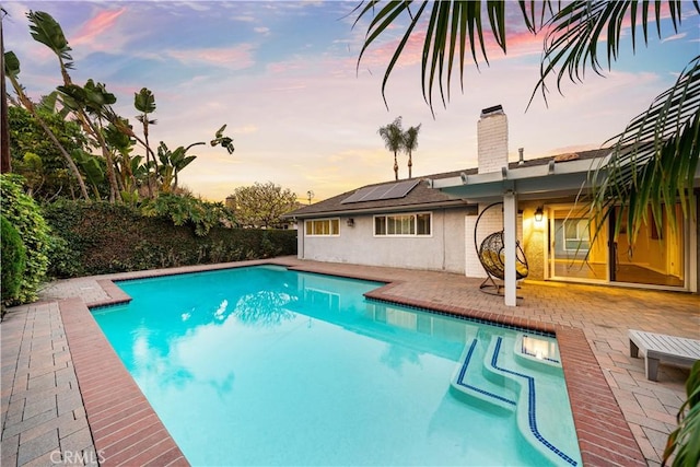 pool at dusk with a patio area