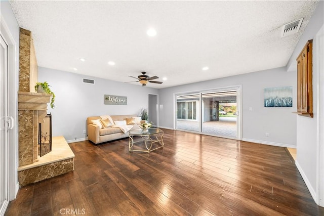 living room with dark wood-type flooring, a high end fireplace, and ceiling fan