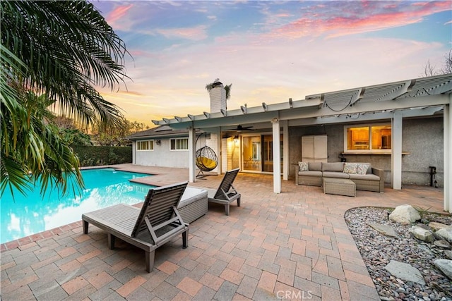 pool at dusk featuring ceiling fan, an outdoor hangout area, and a patio area