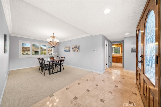 dining space featuring a textured ceiling, ornamental molding, light colored carpet, and a notable chandelier