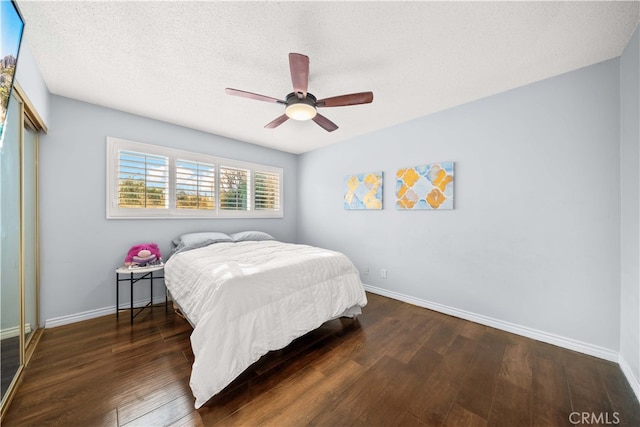 bedroom with ceiling fan, a textured ceiling, and dark hardwood / wood-style floors