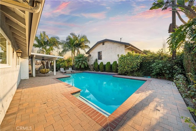 pool at dusk featuring a patio