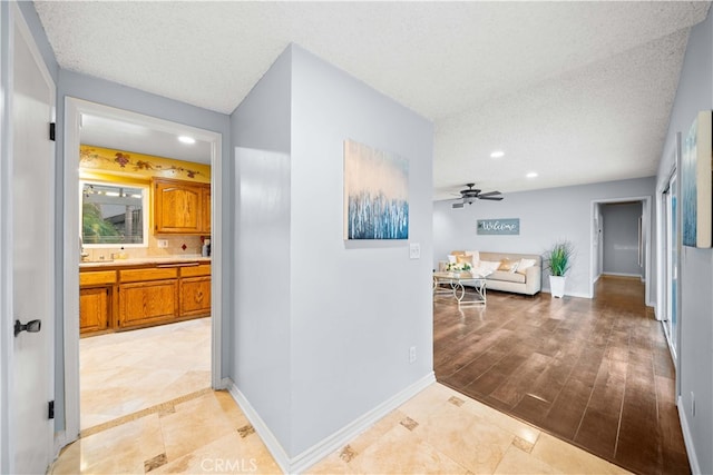 corridor with a textured ceiling and light hardwood / wood-style flooring