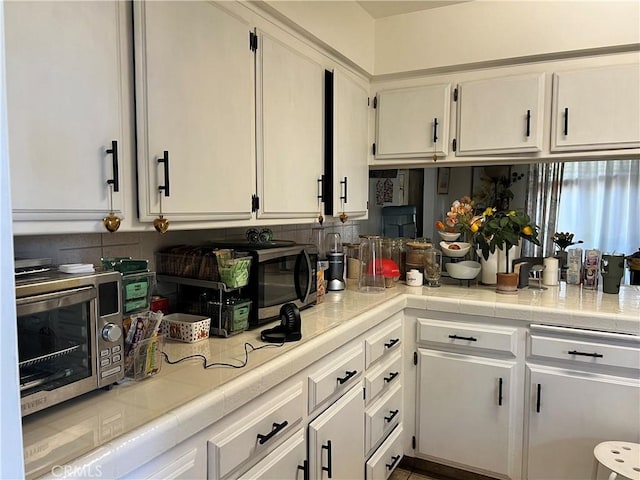 kitchen with tile countertops and white cabinets