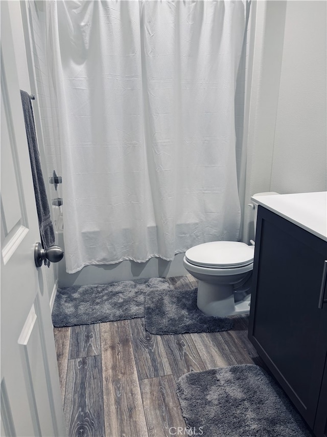 full bathroom featuring wood-type flooring, toilet, vanity, and shower / bathtub combination with curtain