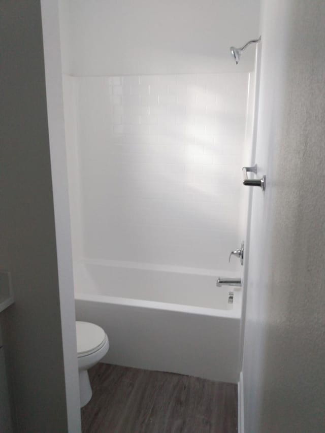 bathroom featuring toilet, hardwood / wood-style flooring, and shower / washtub combination