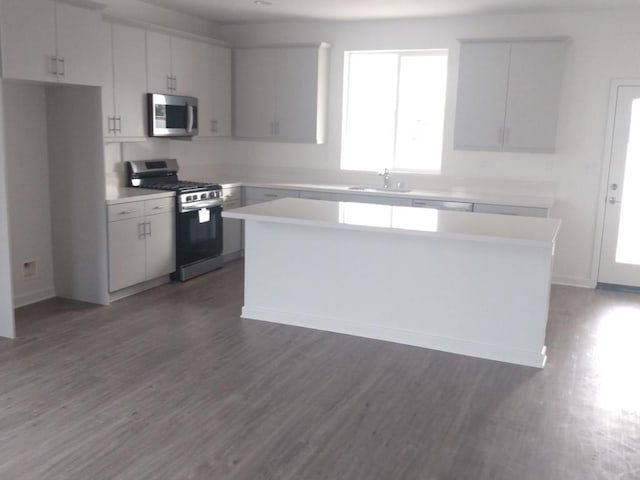 kitchen with sink, white cabinets, appliances with stainless steel finishes, and a kitchen island