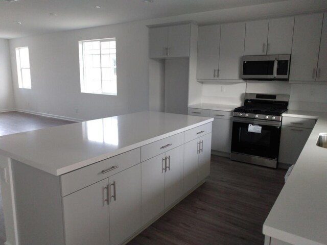 kitchen featuring appliances with stainless steel finishes, white cabinets, dark hardwood / wood-style floors, and a kitchen island