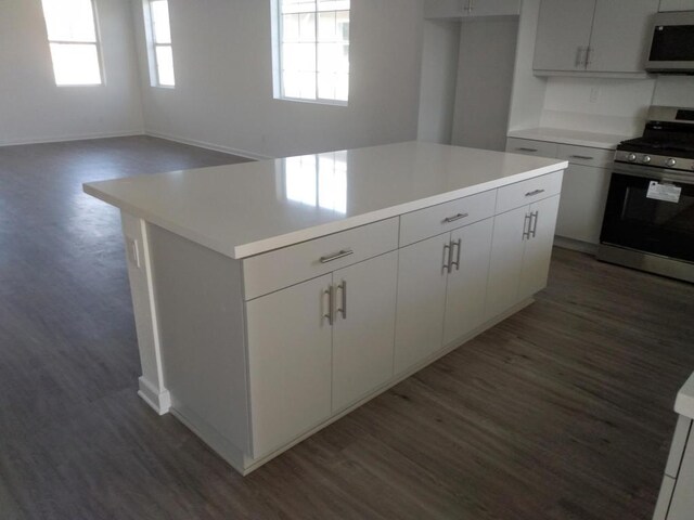 kitchen with stainless steel range, dark hardwood / wood-style floors, a kitchen island, and white cabinets