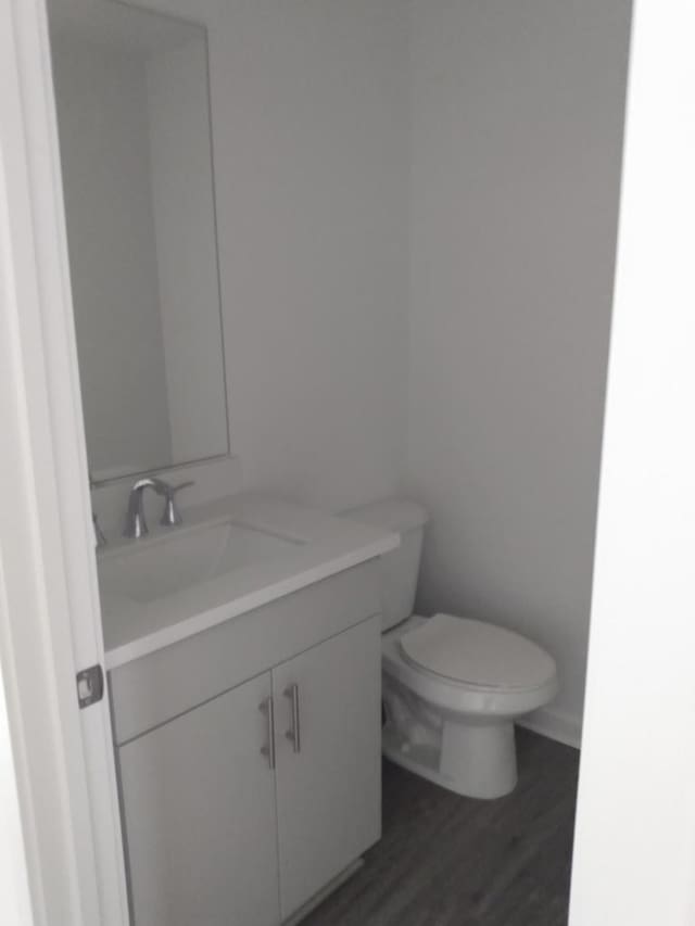 bathroom featuring toilet, hardwood / wood-style flooring, and vanity