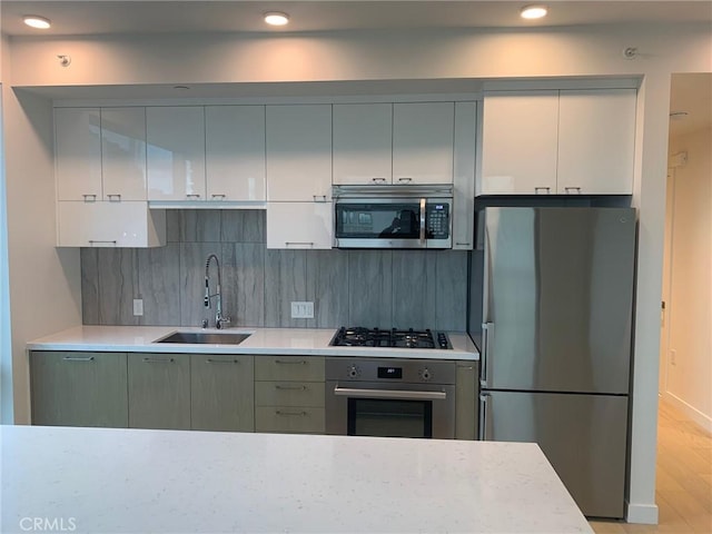 kitchen with light wood-type flooring, stainless steel appliances, backsplash, and sink