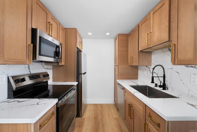 kitchen with decorative backsplash, sink, light hardwood / wood-style flooring, appliances with stainless steel finishes, and light stone counters