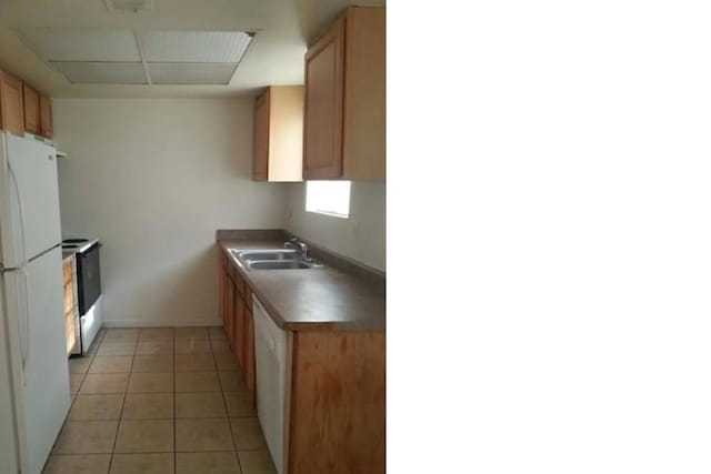 kitchen featuring white appliances, light tile patterned floors, and sink