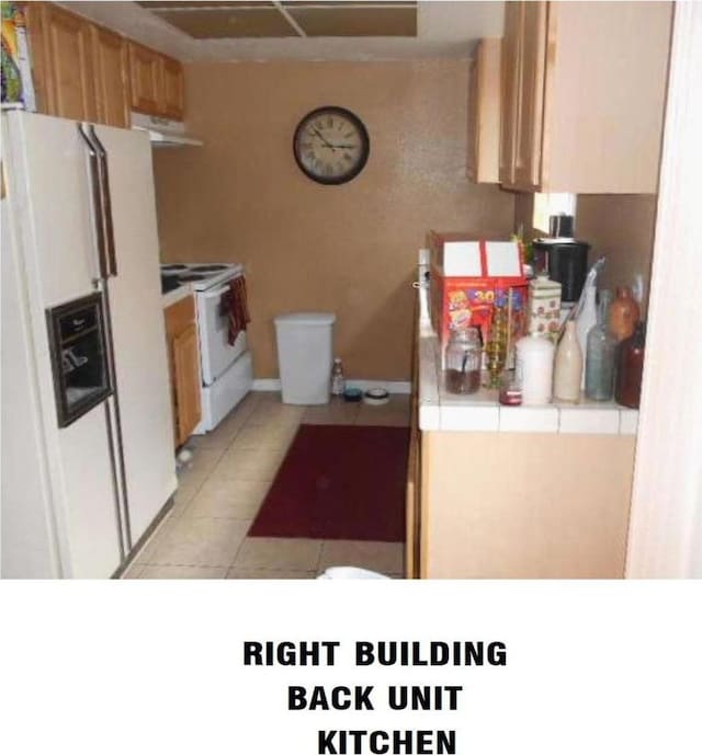 kitchen with exhaust hood, light tile patterned floors, tile counters, and white appliances