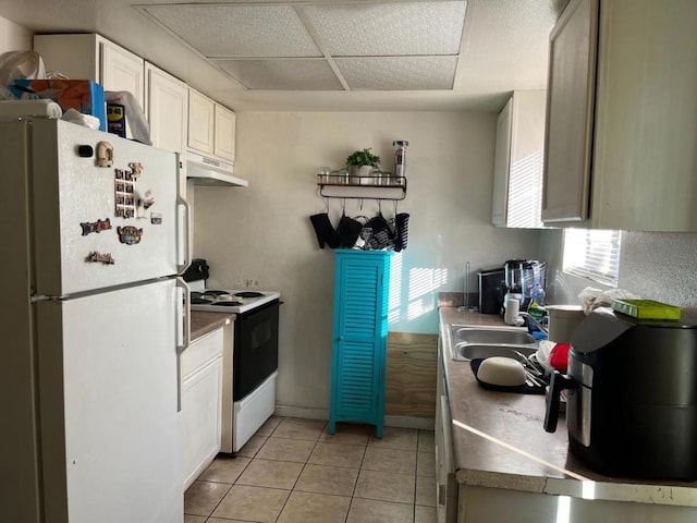 kitchen with light tile patterned floors, white refrigerator, white cabinets, and range with electric cooktop