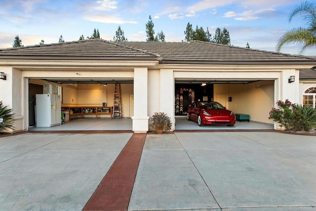 garage featuring white fridge with ice dispenser and driveway