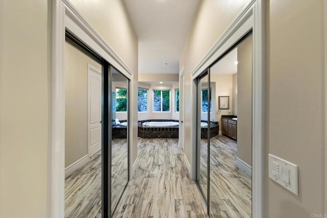 hallway featuring wood finished floors and baseboards