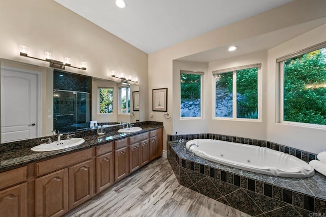 bathroom with double vanity, a tub with jets, a sink, and a shower stall