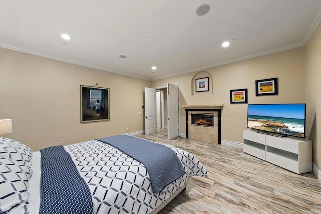 bedroom with baseboards, a tiled fireplace, ornamental molding, wood finished floors, and recessed lighting