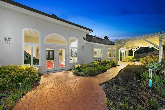 property entrance with stucco siding, a patio area, a pergola, and french doors