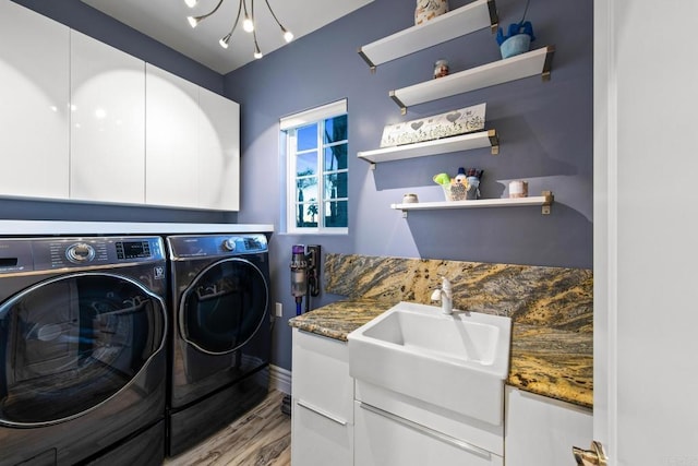 washroom with a chandelier, washing machine and dryer, a sink, wood finished floors, and cabinet space