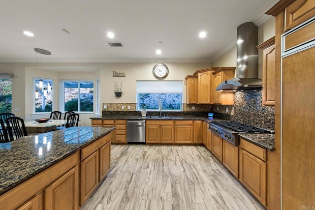 kitchen featuring ornamental molding, appliances with stainless steel finishes, decorative backsplash, wall chimney exhaust hood, and dark stone countertops