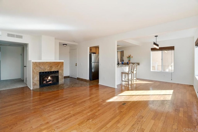 unfurnished living room with light wood-type flooring and a high end fireplace