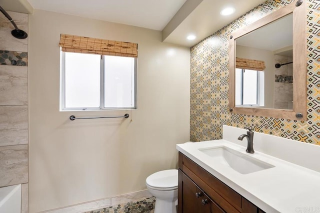 full bathroom featuring tiled shower / bath, vanity, and toilet